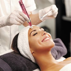 A woman is in a clinic receiving a hydrodermabrasion treatment to her face